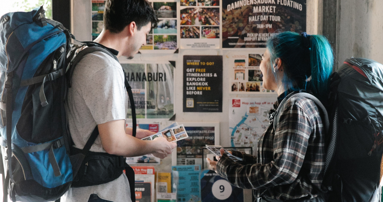 Backpacking couple looking at notice board