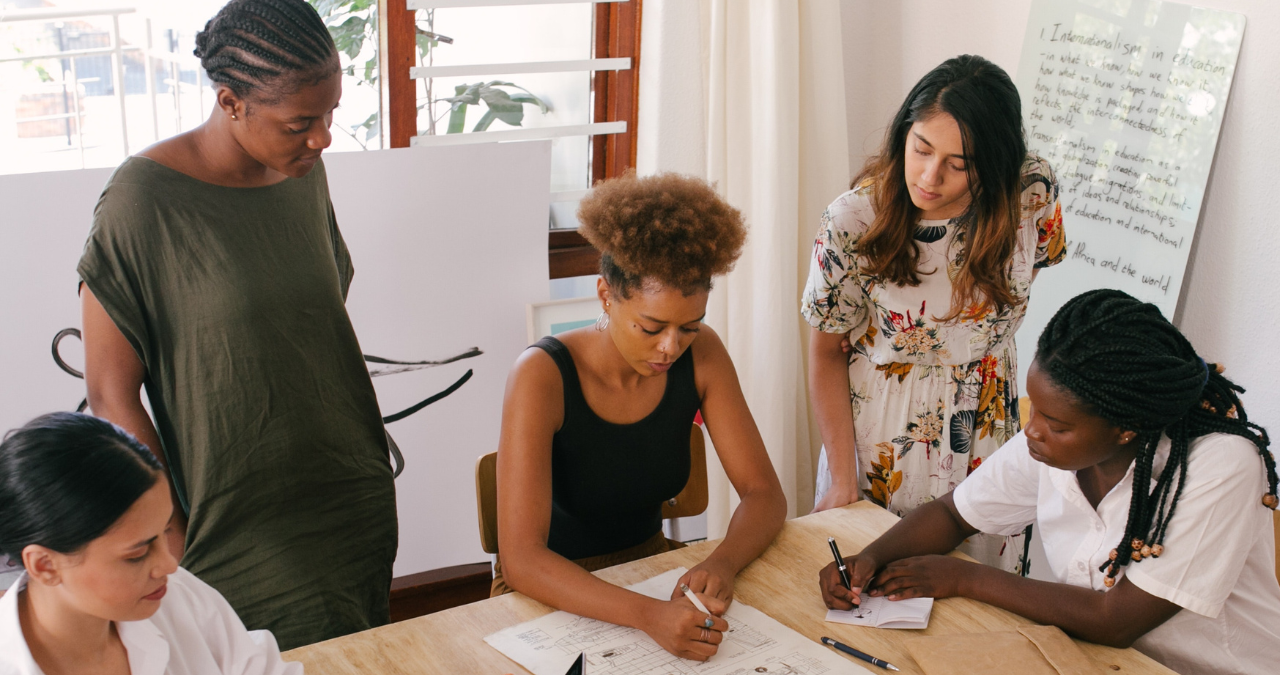 Group of people looking at a spreadsheet and writing.