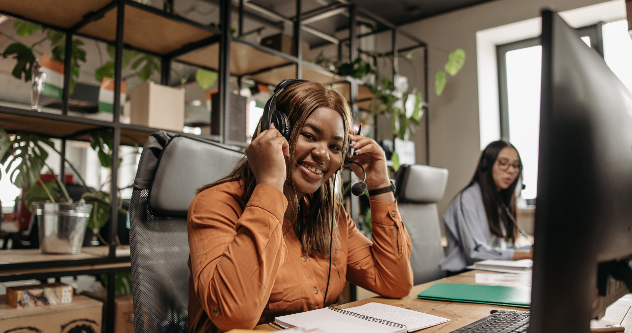 Lächelnde Frau mit Headset bei der Arbeit.