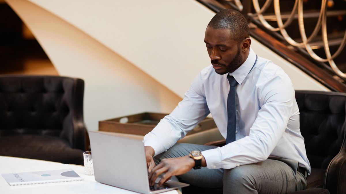 Hotellobby, in der ein Mann an einem offenen Laptop sitzt, in dem künstliche Intelligenz läuft.